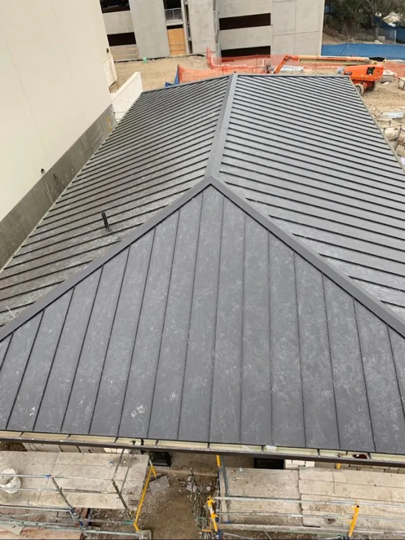 Commercial metal roof construction with crane equipment in DeForest